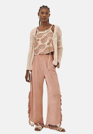 Cárdigan de punto ligero sobre una camiseta de tirantes con estampado floral; pantalones de pierna ancha suaves y rosados con borlas laterales; sandalias casuales.