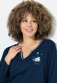 Camiseta de manga larga azul marino con escote en V, que presenta un ribete blanco y una ilustración de un gato con el texto "Gato esponjoso" bordado.