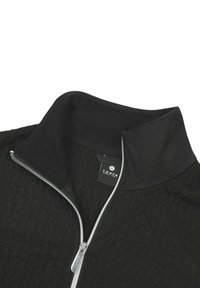 Schwarze Zip-Jacke mit einem strukturierten Muster, Stehkragen und silbernem Reißverschlussdetail. Das Material wirkt weich und leicht.