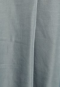 Tecido azul-claro com uma textura suave e delicada; exibe um brilho sutil e um padrão tecido, caindo em suaves dobras.
