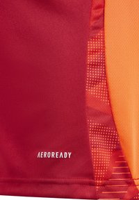 Rode en oranje sportshirt van gladde stof, met een textuurverlooppatroon en een "AEROREADY" label nabij de zoom.