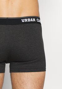 Schwarze Boxershorts aus einem weichen, dehnbaren Material. Mit einem gebrandeten Gummibund, auf dem "URBAN CLASSIC" in kontrastierendem weißen Text steht.