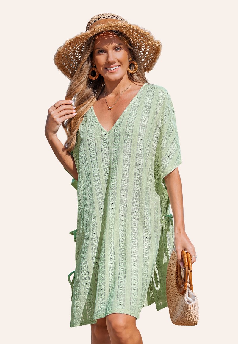 Lichtgroene v-hals cover-up jurk met horizontale gestreepte print, zijstrikjes en een losse pasvorm. Gecompleteerd met een strohoed en een gevlochten tas.