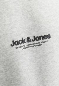 Sweat-shirt en coton gris clair avec un logo brodé noir "Jack & Jones" et un texte supplémentaire en dessous, texture lisse, design décontracté.