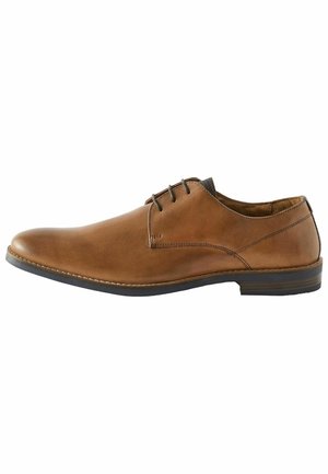 Zapato de vestir de cuero marrón con punta redondeada, detalles cosidos, suela de goma negra y cuatro ojales para los cordones. Textura suave, acentos mínimos.