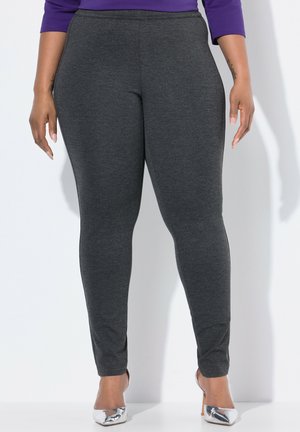 Leggings grises con una textura suave, corte ajustado, cintura elástica y diseño hasta el tobillo. Llevados con zapatos de tacón altos plateados.
