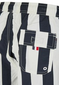 Marineblauwe en witte gestreepte zwemshorts met een elastische tailleband, een achterzak en contrasterende stiksels. Inclusief een klein drie-kleurig accentlabel.