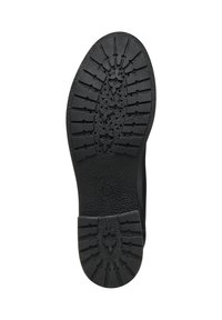 Semelle de chaussure en caoutchouc noir avec un motif de relief texturé. Présente des rainures et des crêtes pour une meilleure adhérence, avec un logo circulaire près du talon.