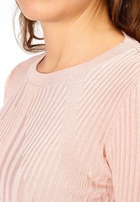 Ljusrosa ribbad tröja med rund hals, som har vertikala ränder och ett strukturerat stickmönster. Mjuk och bekväm tyg.