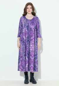 Robe longue à motifs violets avec des manches trois-quarts, dotée d'un col rond et d'une jupe froncée, associée à des bottes de combat noires.
