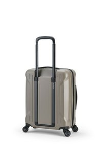 Hartschalenkoffer in Beige mit strukturierter Oberfläche, schwarzem ausziehbarem Griff und vier Rollen für Mobilität. Verfügt über einen Reißverschluss.