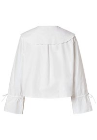 Blouse blanche avec un col festonné, manches longues avec poignets froncés et liens aux poignets. Tissu lisse et léger.