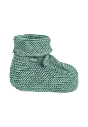 Petit chausson vert tricoté pour bébé avec revers plié et bride à l'avant sur fond blanc.