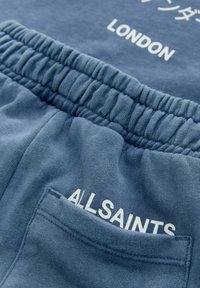 Blå bomulds-sweatpants med ribbet talje, hvid tekst "ALLSAINTS" og "LONDON", samt en baglomme med en ren finish.