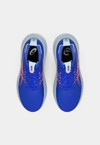 Niebieskie buty sportowe z siateczkową cholewką, z różowymi akcentami i sznurówkami, odblaskowymi detalami oraz wyściełaną szaro-skalową podeszwą.