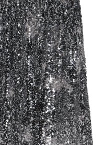 Robe noire et argent couverte de sequins, présentant une surface texturée et un design en cascade qui reflète la lumière dans plusieurs directions.