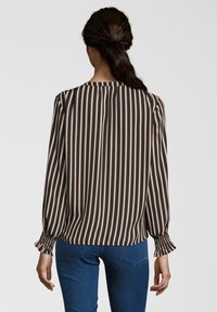 Halenka s dlouhým rukávem a vysokým výstřihem, s vertikálními pruhy v tmavě hnědé a světle růžové barvě, s nařasenými manžetami a hladkým textilním povrchem.