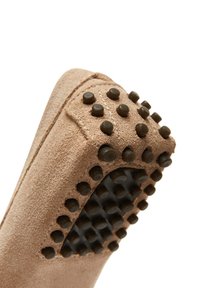 Scarpa in suede marrone chiaro con superficie texturizzata. La suola presenta tasselli in gomma scura per una presa sicura. Linee pulite e un design minimale ne aumentano la versatilità.