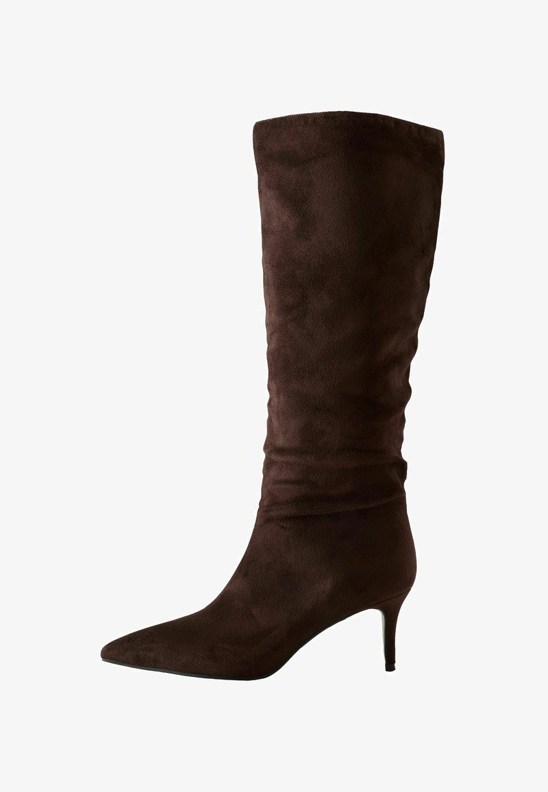 Rjavi nubuk škornji do kolen z ostrim nosom in tankim petam. Oblika vključuje guban vzorec blizu vrha za dodatno podrobnost.