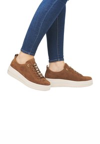 Sneaker in suede marrone con una suola spessa bianca, design con lacci e occhielli in tono oro. Il dettaglio laterale presenta una linguetta per una facile calzata.