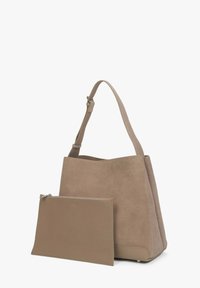 Beżowa torebka zamszowa typu tote z płaską torebką na zamek. Strukturalny kształt, szerokie otwarcie u góry, regulowany pasek, gładkie akcenty na dnie.