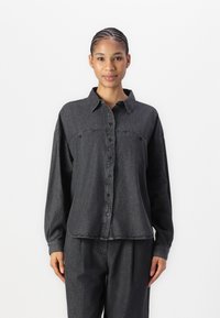 Camisa de botão em denim cinza escuro com colarinho, bolso único no peito e mangas longas. O tecido é ligeiramente texturizado e tem um corte descontraído.