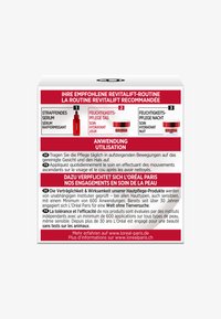 Red and white packaging featuring skincare instructions in multiple languages. Contains three product steps: serum, day cream, and night cream.