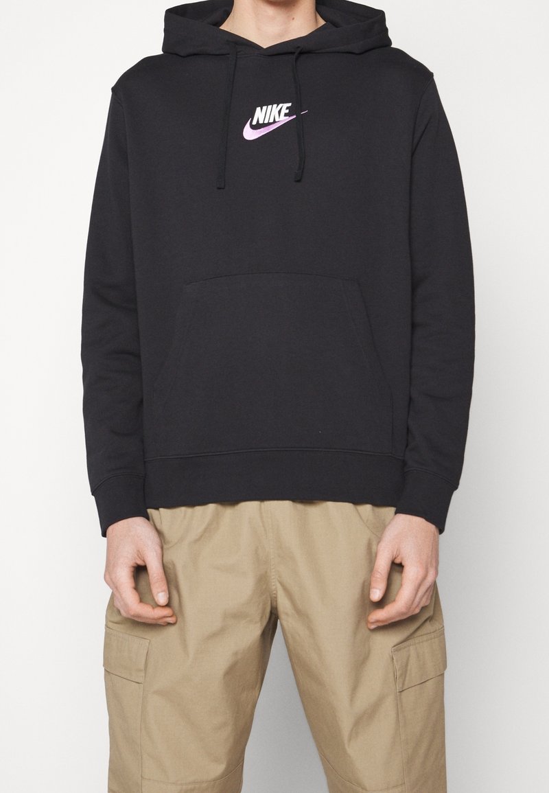 Svart hoodie i bomullsblandning med en känguruficka och en rosa Nike-logotyp på bröstet, kombinerad med beige cargobyxor.