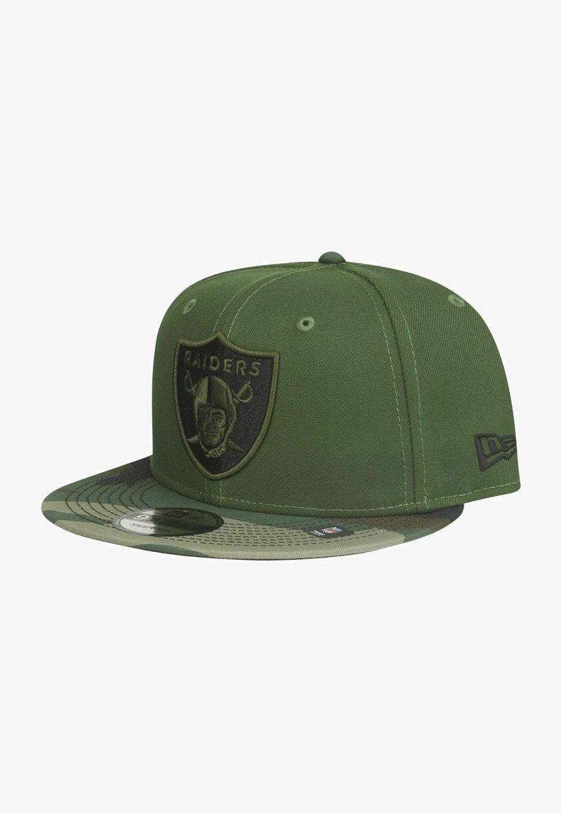 Grüne Baseballmütze mit einem schwarzen Raiders-Logo auf der Vorderseite, einem Schirm im Camouflage-Muster und einem strukturierten Design mit Nähdetails.