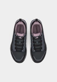 Pari mustia ja harmaita Adidas Terrex -polkujuoksukenkiä, joissa on vaaleanpunainen sisäpinta, nähtynä ylhäältä valkoisella taustalla.