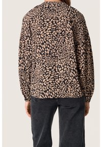 Blusa nera con un motivo a macchie astratte beige. Presenta maniche lunghe a sbuffo e scollatura rotonda, realizzata in tessuto morbido.