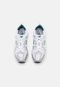 Un par de zapatillas de running New Balance en blanco y verde vistas desde arriba sobre un fondo blanco liso.