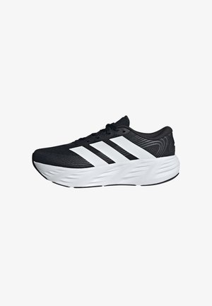 Zapatilla de correr negra con suela blanca y tres gruesas rayas blancas en el lateral, con una entresuela texturizada y cierre de cordones.