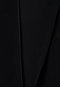 Sort zip-up hoodie med glat stof, en tekstureret inderside og et subtilt prægede logo på brystområdet.