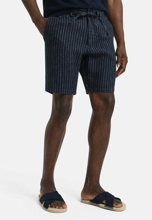 Marine gestreifte Shorts mit einem Kordelzugbund, aus leichtem Stoff gefertigt. Verfügt über seitliche Taschen und eine lockere Passform. Getragen mit dunklen Sandalen.