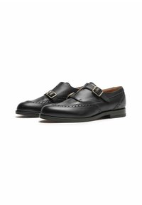 Scarpe in pelle nera con punta tondeggiante, dettagli decorativi a brogue e doppio cinturino con fibbie color oro. Suola nera piatta.