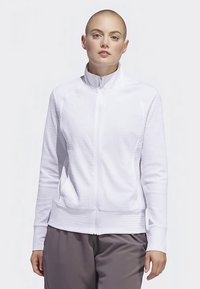 Fehér zipzáras dzseki struktúrált mintával, magas gallérral és bordázott mandzsettákkal. Oldalzsebekkel és testhez simuló kialakítással rendelkezik.