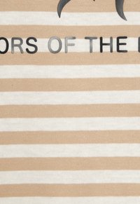 Beige and white striped textile with vertical stripes. Features black text reading "COLORS OF THE EARTH." Soft knit texture.
