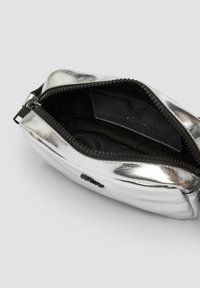 Hopeanvärinen metallinhohtoinen vetoketjullinen pussukka, jossa on sileä pinta, musta sisävuori ja korttitasku. Kompakti, pyöreä muoto.