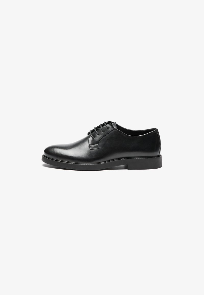 Black leather lace-up shoe with a rounded toe, smooth texture, minimal stitching, and a low rubber heel for stability.