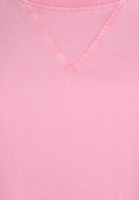 V-hals t-shirt i lyserød bomuldsstof; glat tekstur med synlige sømme langs halsudskæringen.