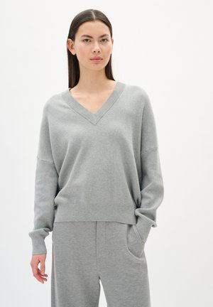 Gray v-neck sweater with long sleeves, made of soft fabric. Relaxed fit; worn with matching gray pants. Simple, seamless design.