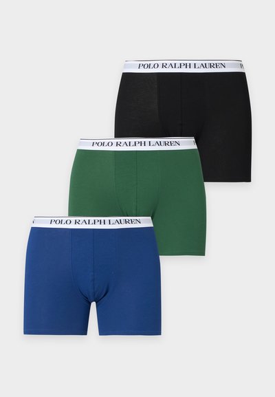 Τρία ζεύγη boxer Polo Ralph Lauren σε μαύρο, πράσινο και μπλε με λευκές branded ζώνες μέσης τοποθετημένα σε φωτεινό φόντο.