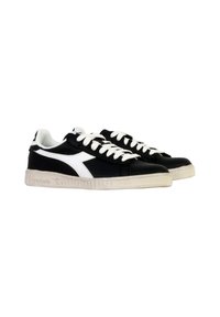 Sorte og hvide sneakers med en glat læderoverdel, hvide snørebånd, en tekstureret gummisål og et karakteristisk logo på siden.