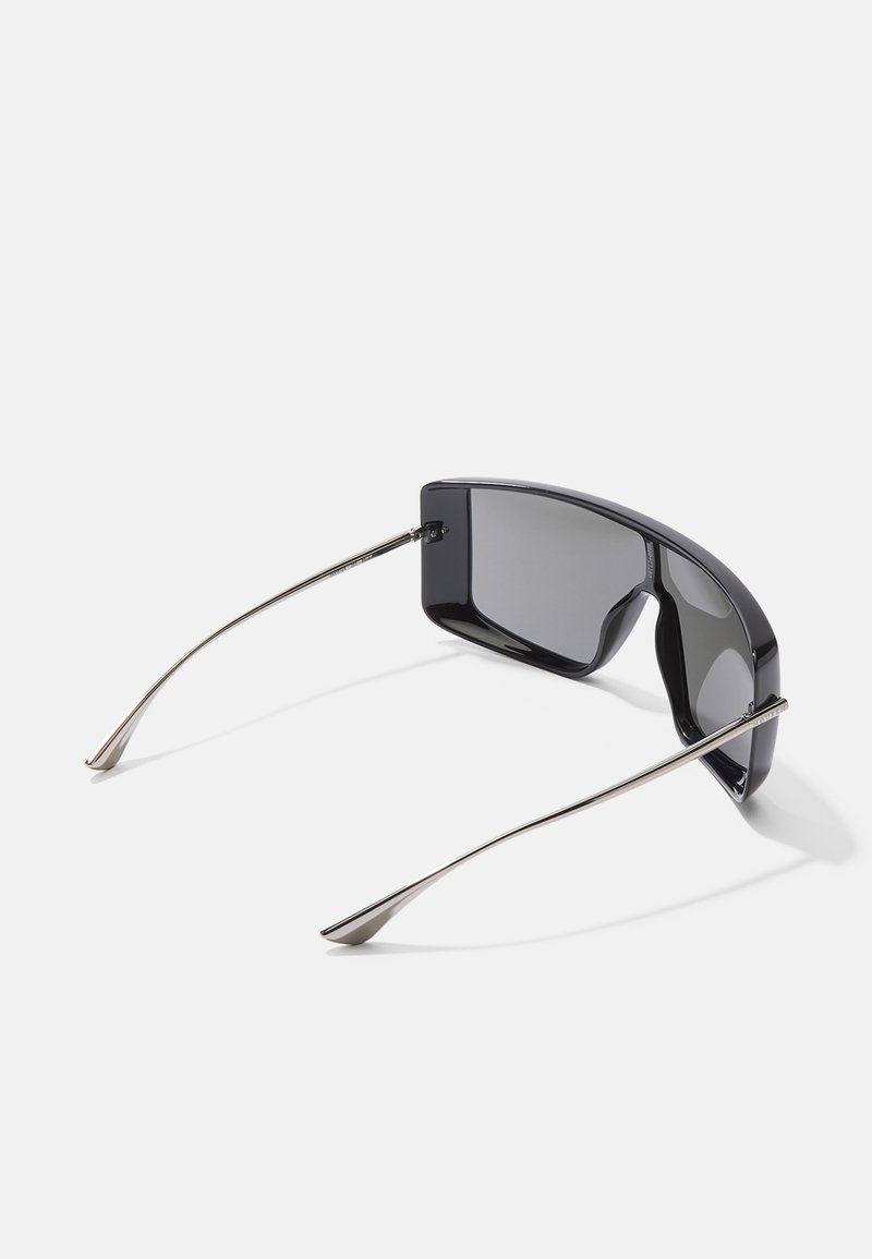 Schwarze Sonnenbrille mit einem eleganten, kantigen Design. Ausgestattet mit grauen Gläsern und dünnen metallischen Bügeln mit spitzen Enden. Hochglänzende Oberfläche auf den Rahmen.
