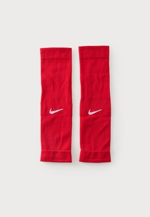 Paire de manchons de jambe athlétiques rouges Nike avec logos swoosh blancs sur chaque manchon, posés à plat sur un fond clair.