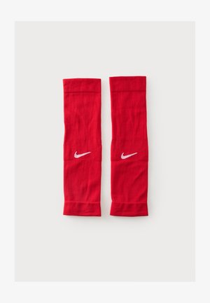 Paire de manchons de jambe athlétiques rouges Nike avec logos swoosh blancs sur chaque manchon, posés à plat sur un fond clair.