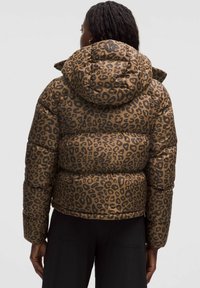 Hnědá péřová bunda s leopardím potiskem, kapucí a prošívanou texturou. Design zahrnuje úzký lem a elastické manžety.