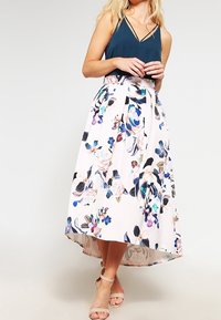 Blommig midikjol med hög-låg fåll, med vit bas och flerfärgade blommönster. Tillverkad av lättviktig tyg med veck.