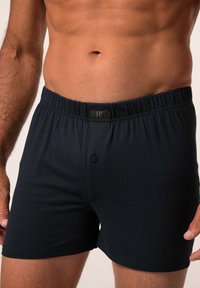 Tmavě modré bavlněné boxerky s elastickým pasem, s jedním knoflíkem na přední části a minimálními švy. Měkká textilie.